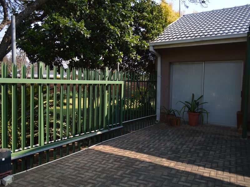 A paved driveway area featuring a sliding security gate, tiled roof structure, and sliding glass door access to the property.