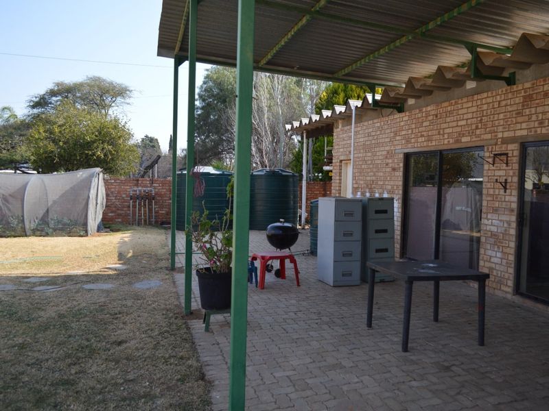 A covered outdoor patio area featuring brick walls, paved flooring, and direct access to the garden through sliding glass doors.