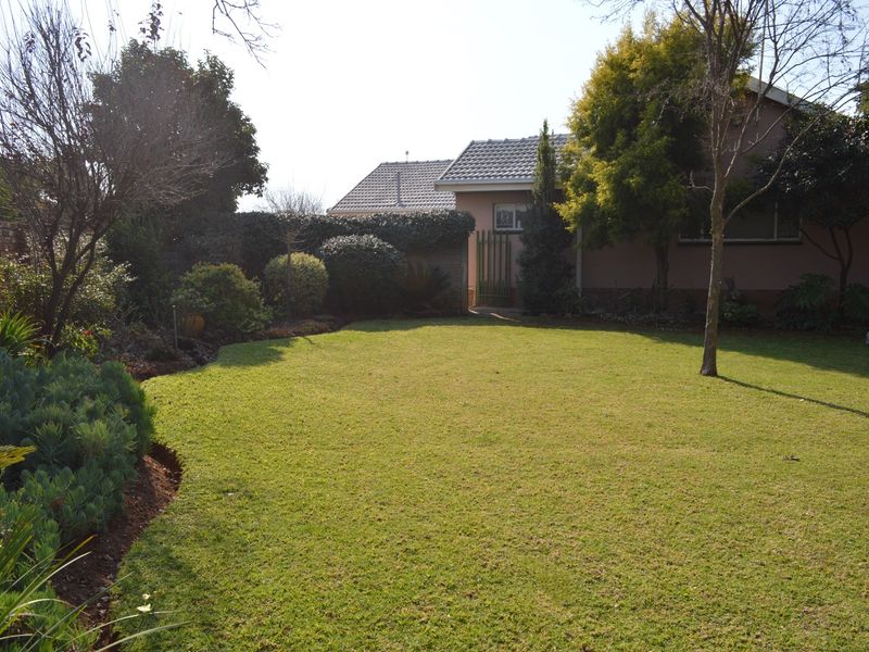 A well-maintained private rear garden featuring a spacious lawn, established landscaping, and secure side access to the property.