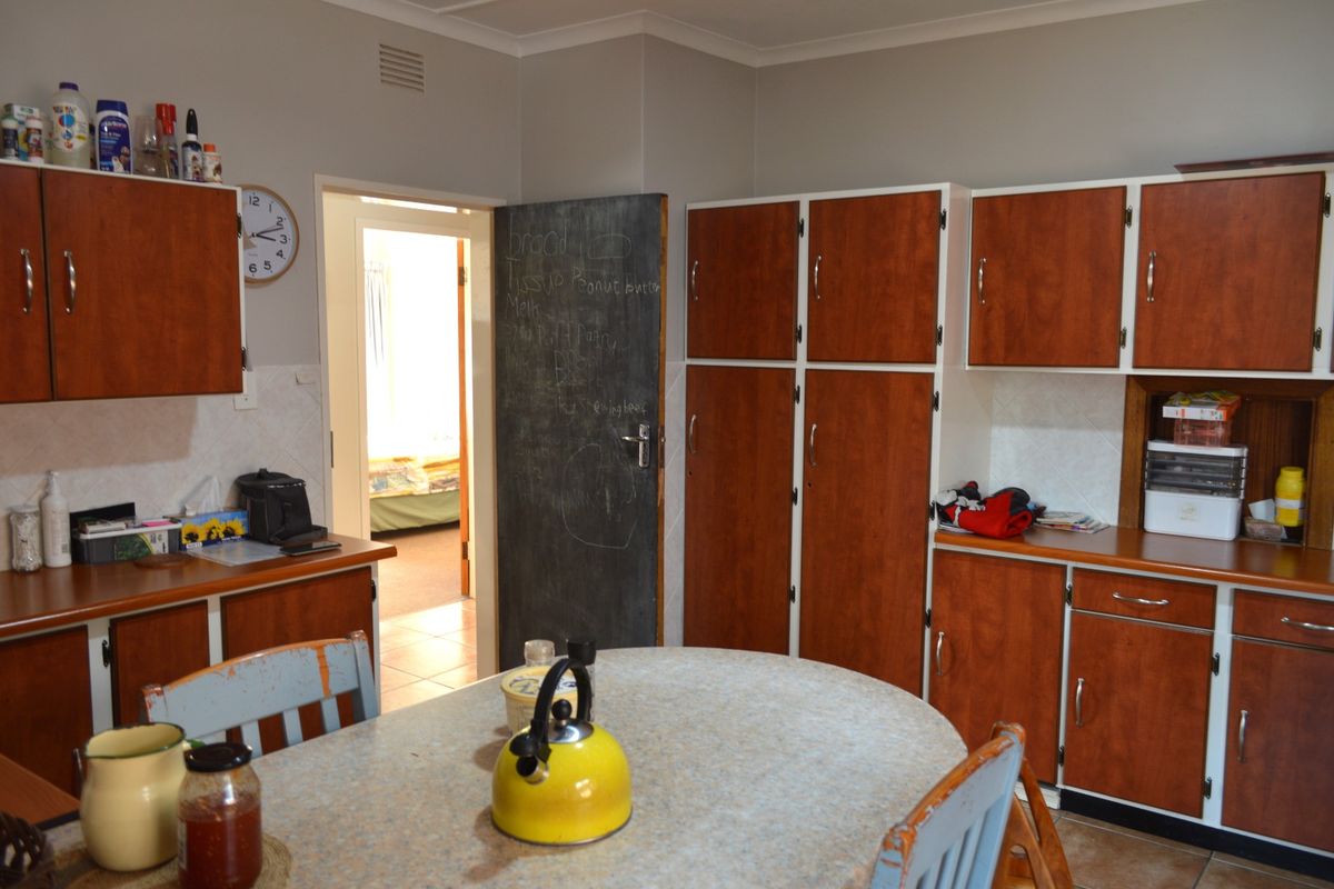 A dated kitchen featuring wood-look cabinetry, laminate countertops, and a tiled backsplash, offering potential for a modern renovation.