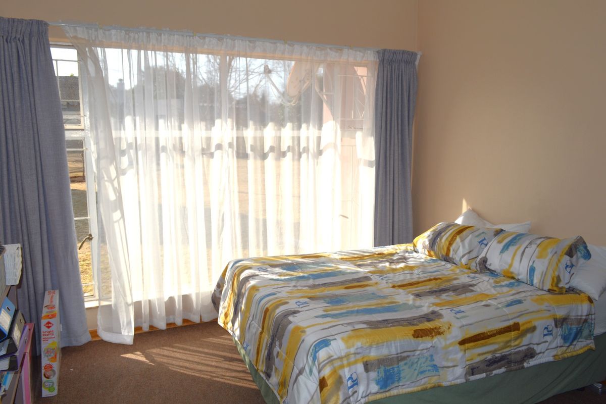 A bedroom featuring a large window with natural light and carpeted flooring.
