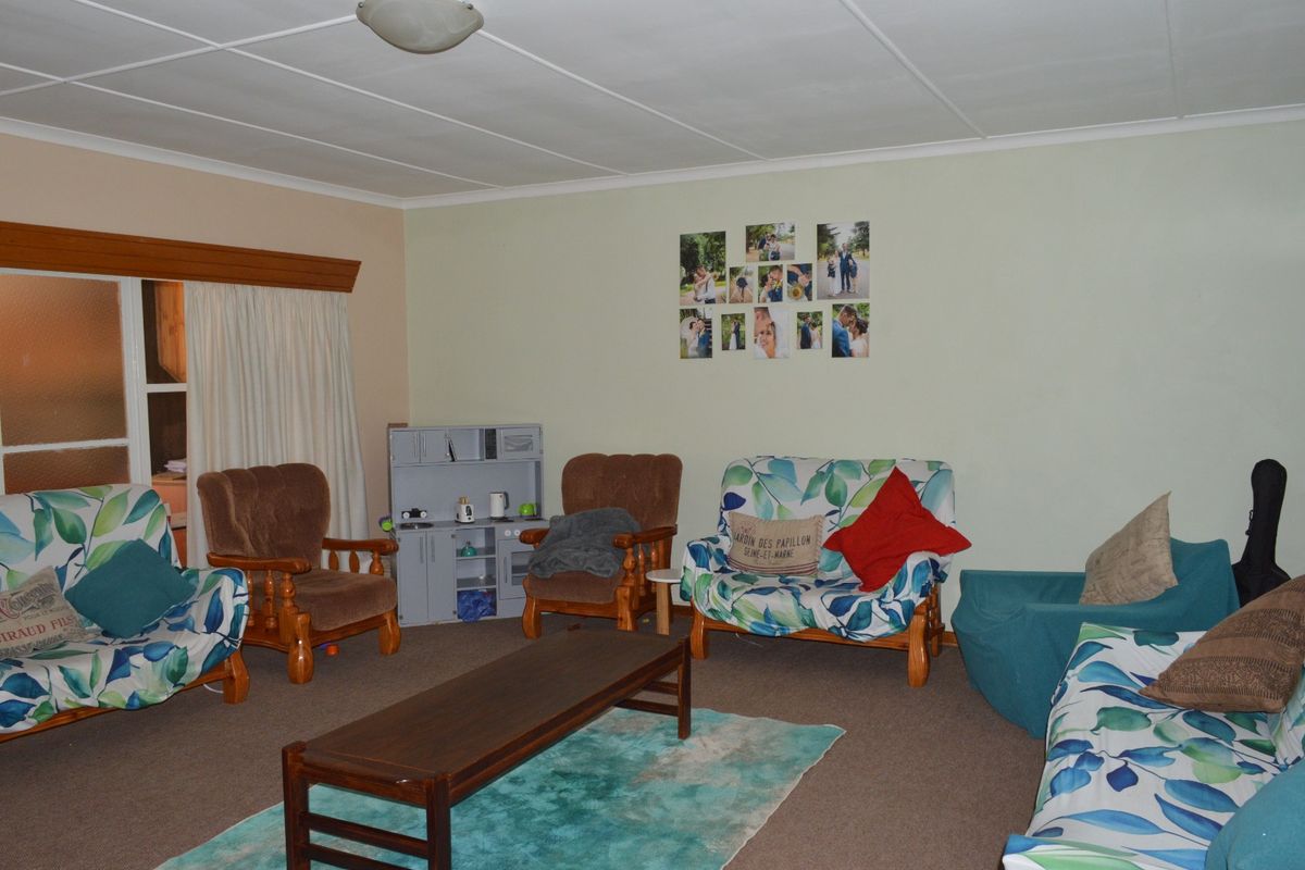 A spacious living room featuring carpeted flooring and a sliding door, offering a functional layout ready for modern updates.