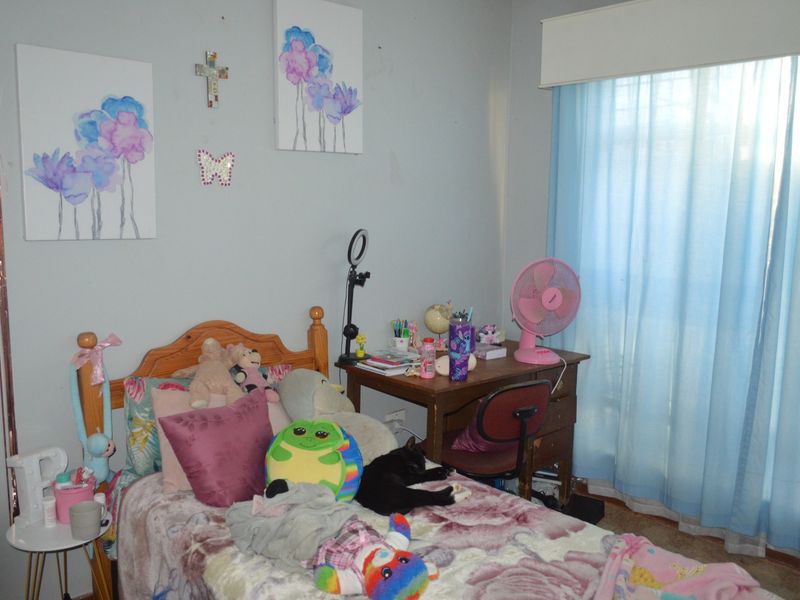 A standard bedroom featuring a window with blue curtains and neutral wall finishes.