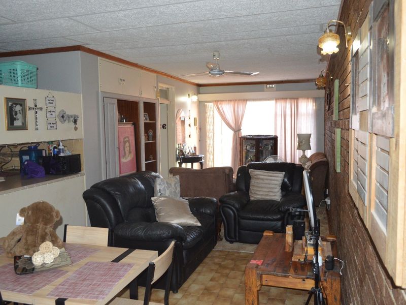 Open-plan living and dining area featuring an exposed brick wall, tiled flooring, and direct access to the patio through sliding glass doors.
