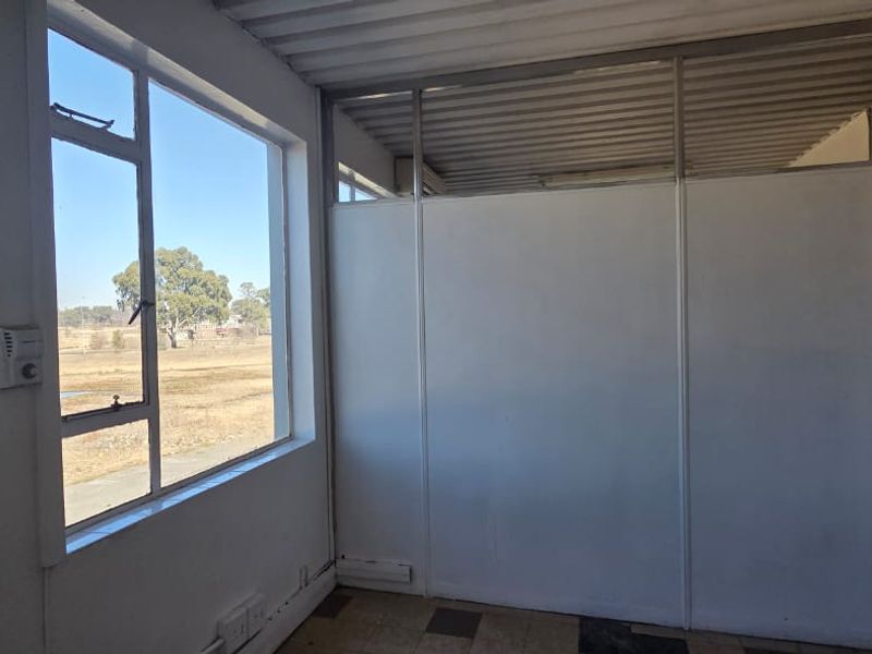 A vacant office space featuring large windows, partition walls, and vinyl flooring, offering a functional layout suitable for commercial use.