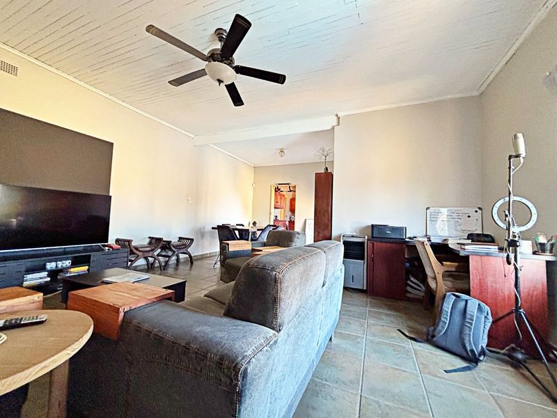 Spacious open-plan living area featuring tiled flooring, a ceiling fan, and timber-look ceiling panels, offering a versatile layout for lounge and dining arrangements.
