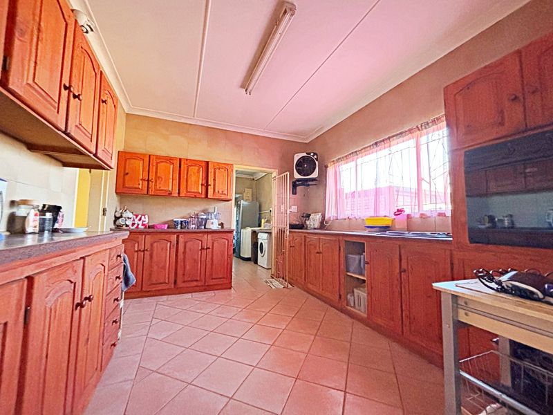 A functional kitchen featuring traditional wooden cabinetry, tiled flooring, and a built-in oven, offering a classic layout with potential for modern updates.