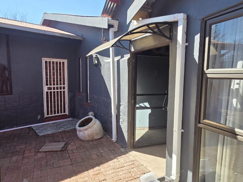 Rear courtyard area featuring brick paving, security gate access, and an awning over the entrance.