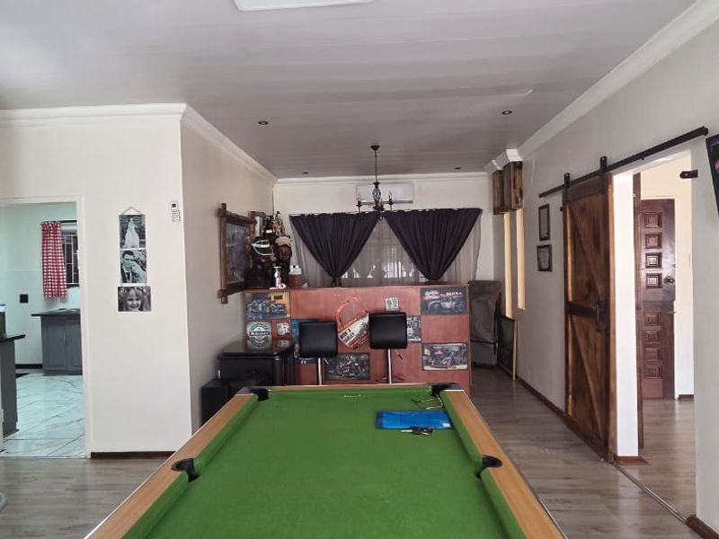 Spacious living area featuring an exposed brick accent wall, sliding barn door, and recessed lighting, currently utilized as a recreational space.