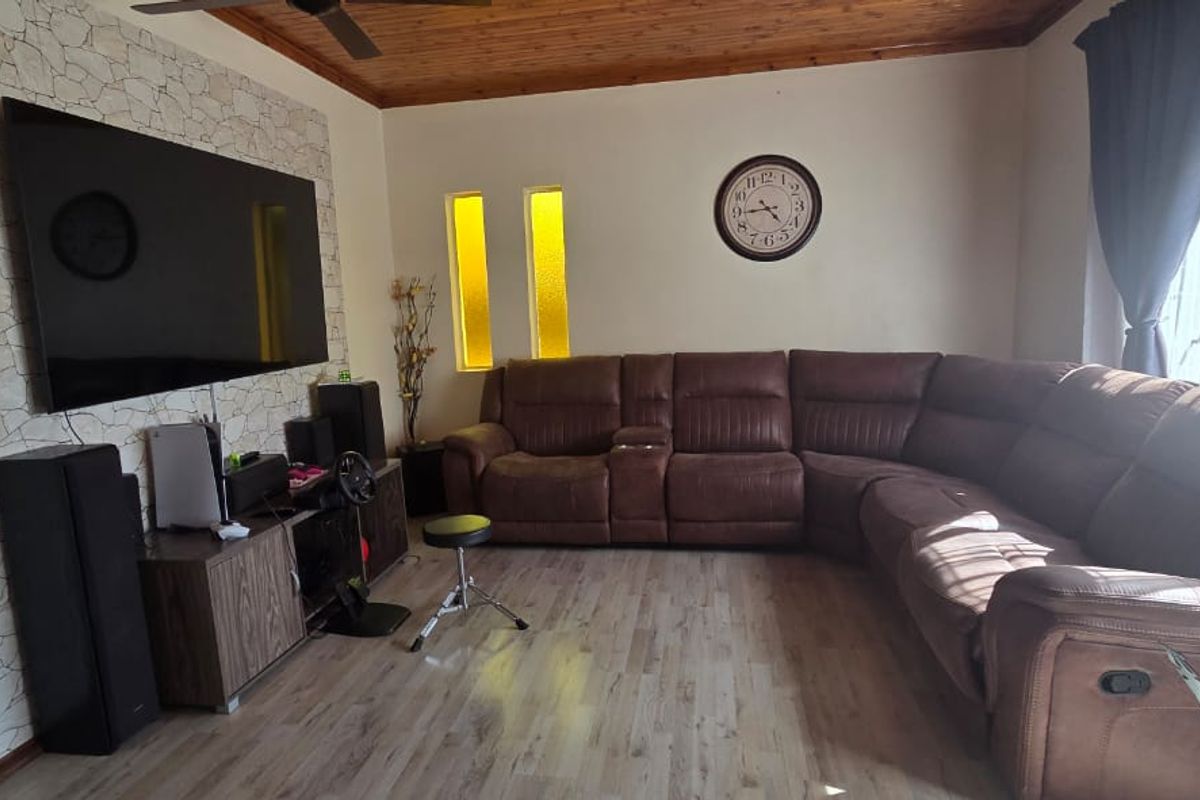 A living room featuring a timber ceiling, laminate flooring, and a stone feature wall with vertical accent windows.
