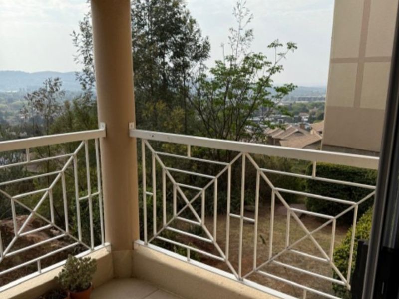 A covered balcony featuring a decorative metal balustrade, tiled flooring, and elevated views of the surrounding landscape.