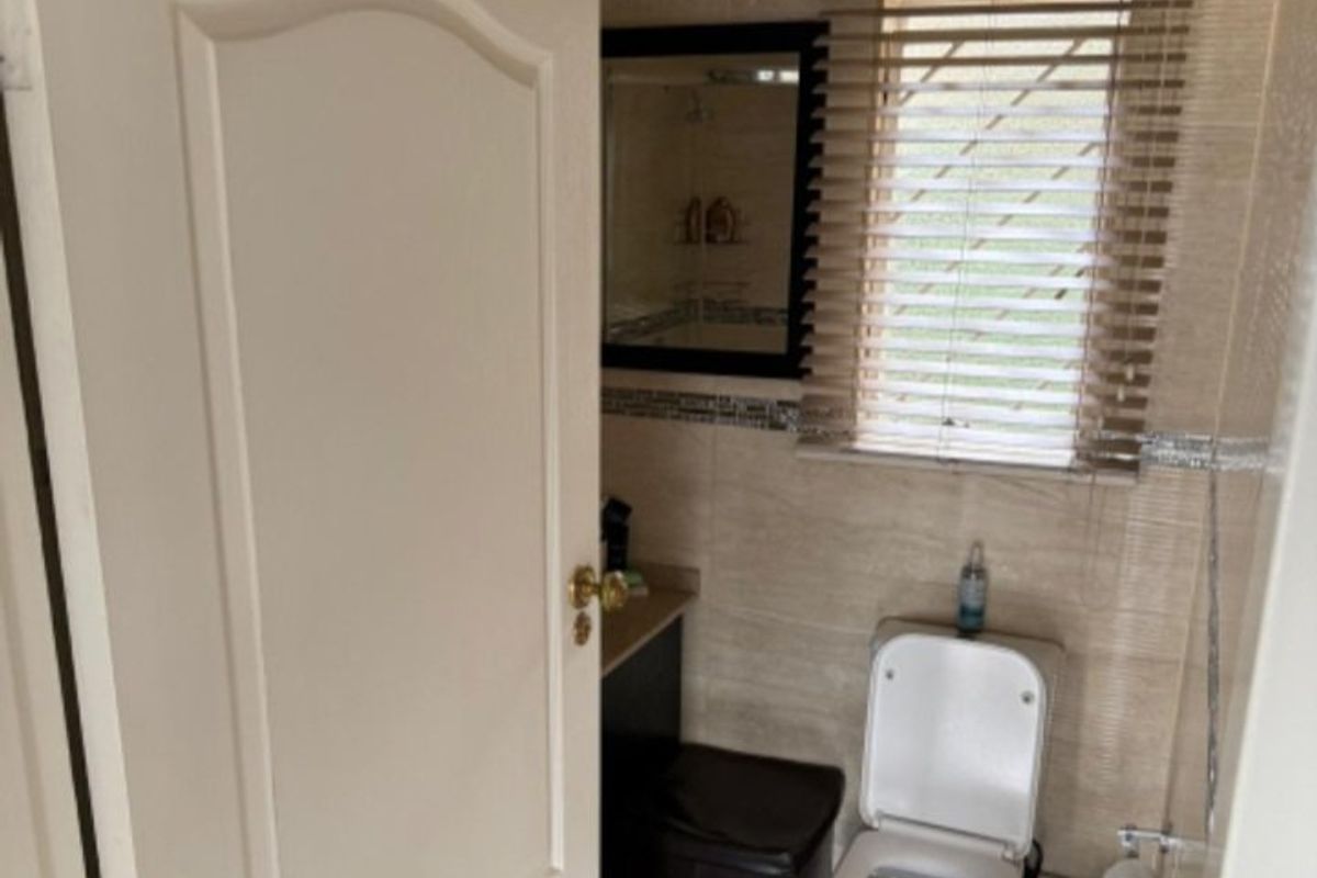 A compact bathroom featuring tiled walls and flooring, a standard toilet, and a vanity mirror, providing a functional space.