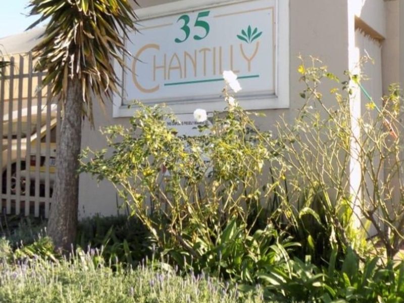 Exterior view of the Chantilly complex entrance, featuring established garden landscaping and clear building signage.