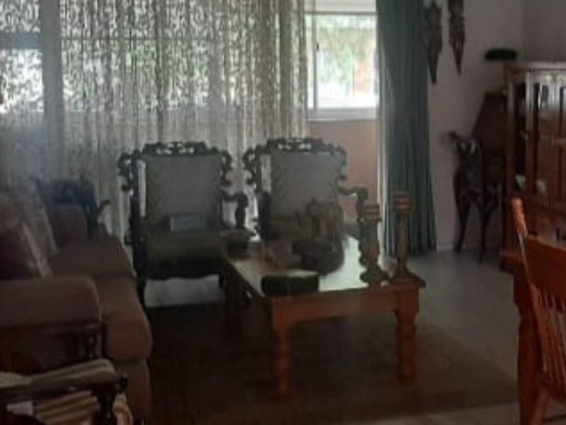 A living room area featuring tiled flooring and a large sliding glass door with curtain treatments, providing access to an outdoor space.