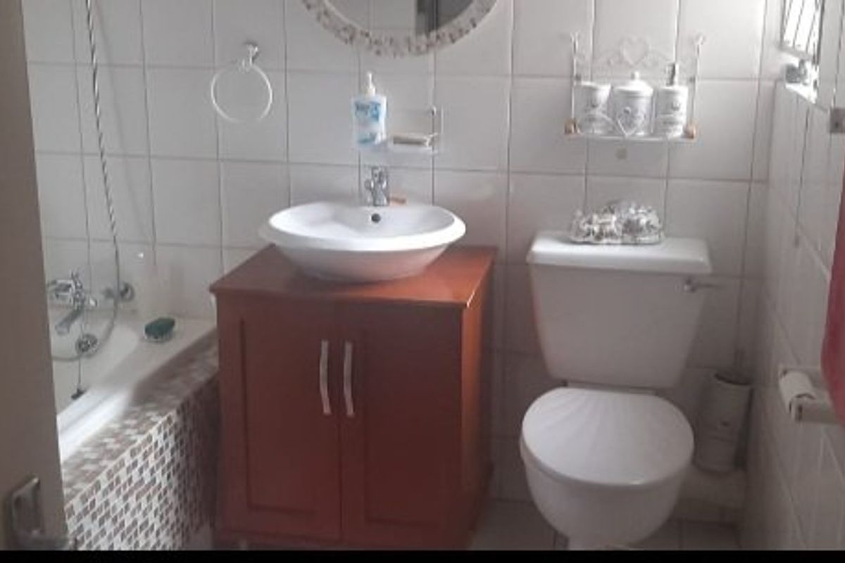 A functional bathroom featuring a vanity with a vessel sink, a standard toilet, and a bathtub with tiled surround.