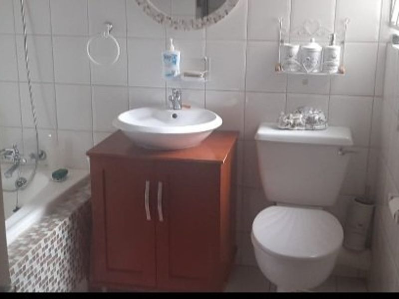 A functional bathroom featuring a vanity with a vessel sink, a standard toilet, and a bathtub with tiled surround.