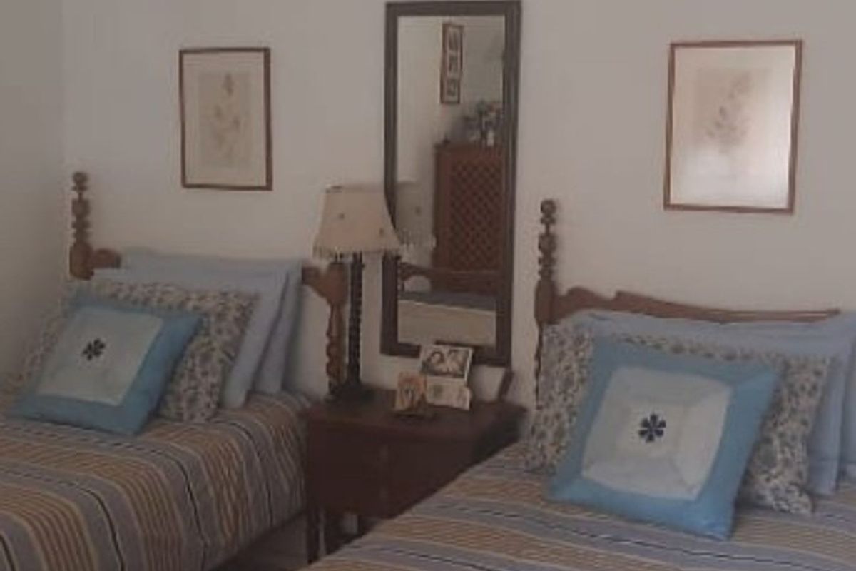 A bedroom featuring two twin beds with a shared nightstand and wall-mounted mirror.