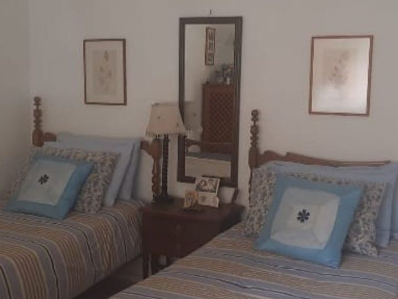 A bedroom featuring two twin beds with a shared nightstand and wall-mounted mirror.