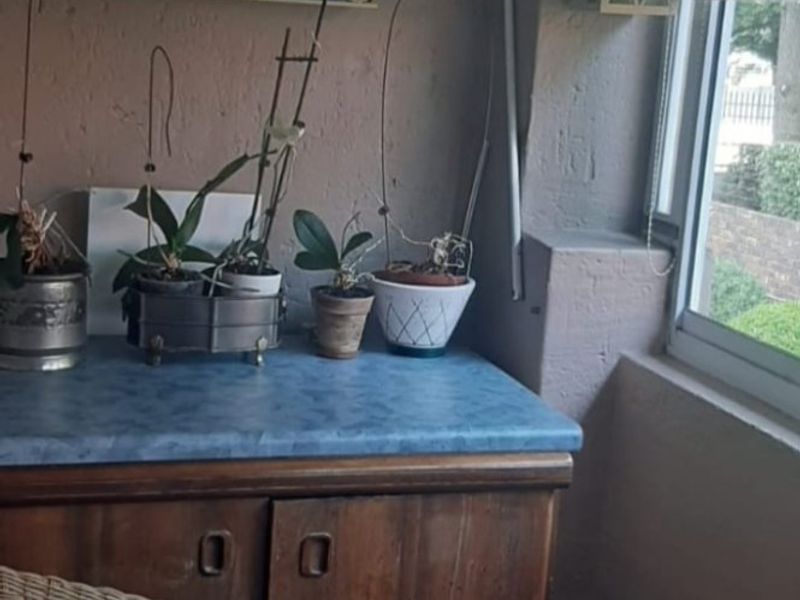 A small covered patio or balcony area featuring built-in wooden cabinetry with a blue laminate countertop and a sliding window.