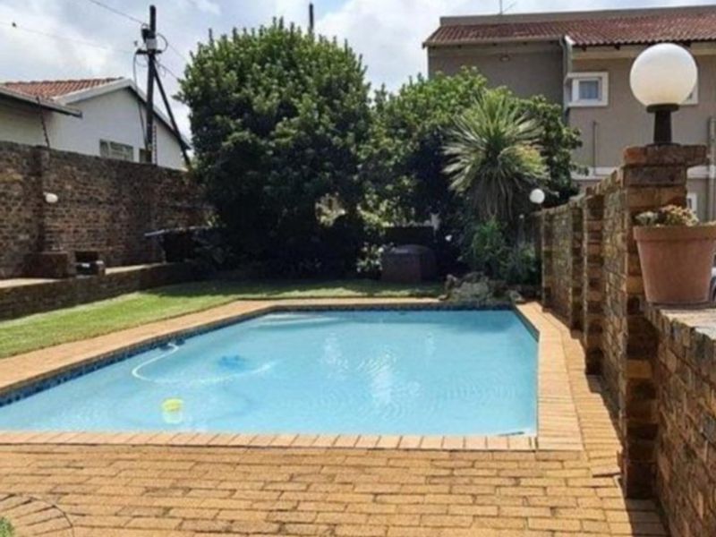 Outdoor pool area featuring a swimming pool, brick paving, and a surrounding brick boundary wall.