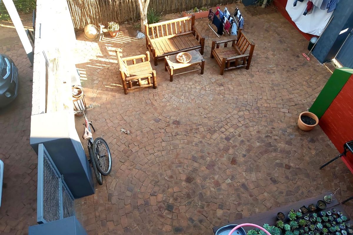 An elevated view of a paved rear courtyard area featuring brick paving and perimeter boundary walls.