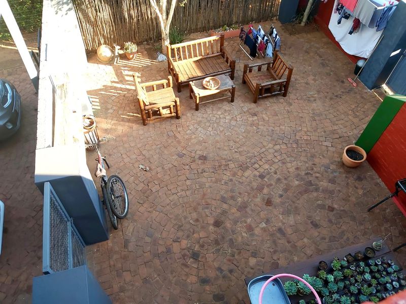 An elevated view of a paved rear courtyard area featuring brick paving and perimeter boundary walls.