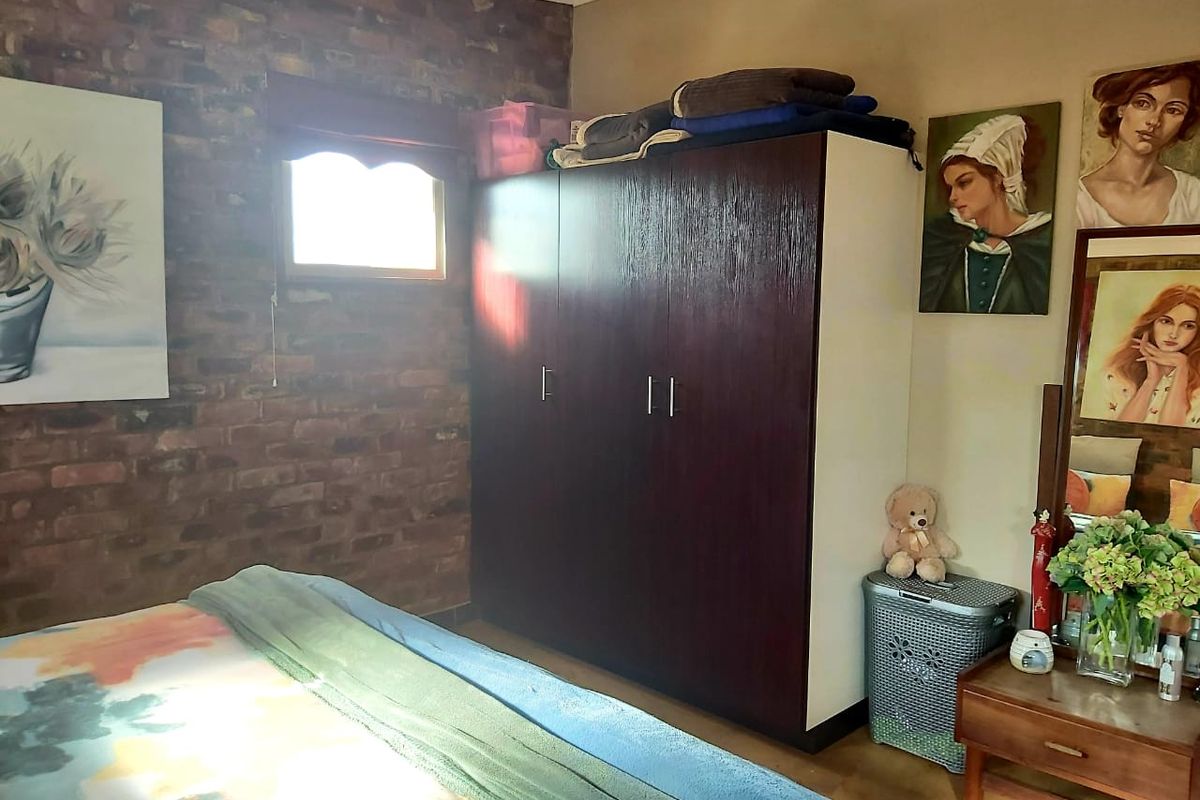 Bedroom featuring an exposed brick feature wall and a large built-in wardrobe providing ample storage space.