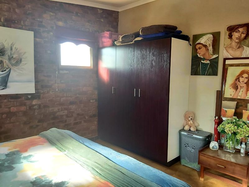 Bedroom featuring an exposed brick feature wall and a large built-in wardrobe providing ample storage space.