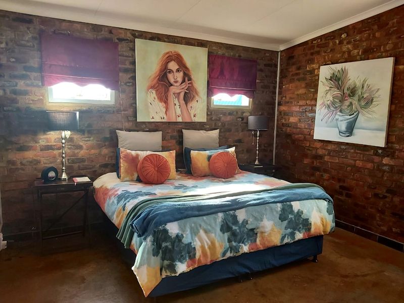 A cozy bedroom featuring rustic exposed brick walls and polished concrete flooring, creating a warm and industrial-inspired atmosphere.