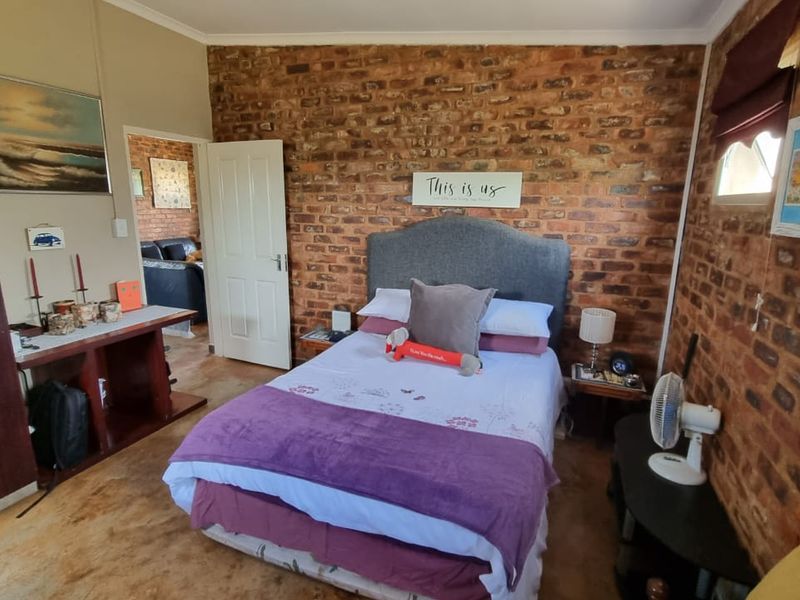 A bedroom featuring rustic exposed brick walls and a neutral layout, offering a warm and textured aesthetic.