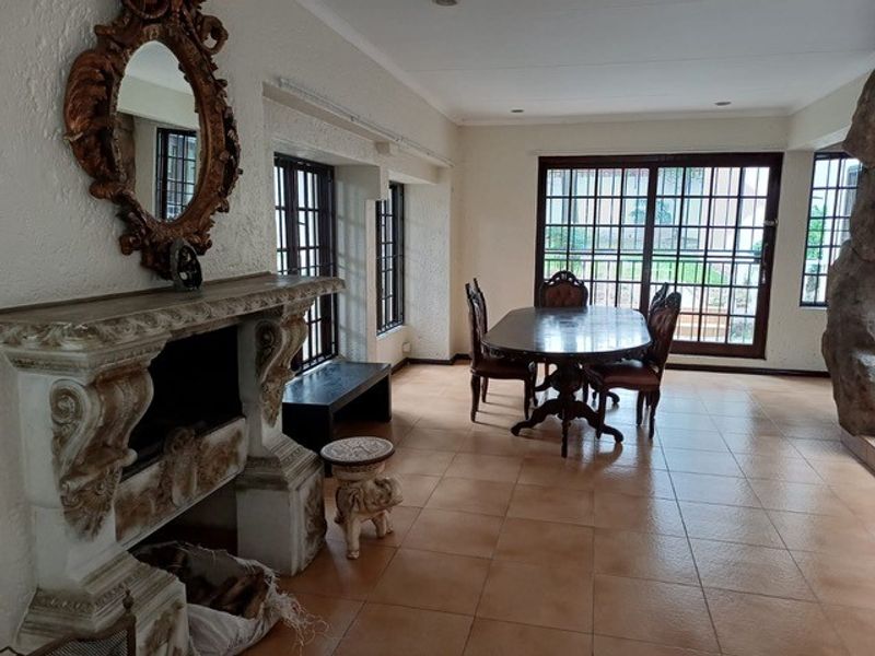 Spacious dining area featuring a prominent ornate stone fireplace, ceramic tile flooring, and large sliding glass doors providing access to the exterior.
