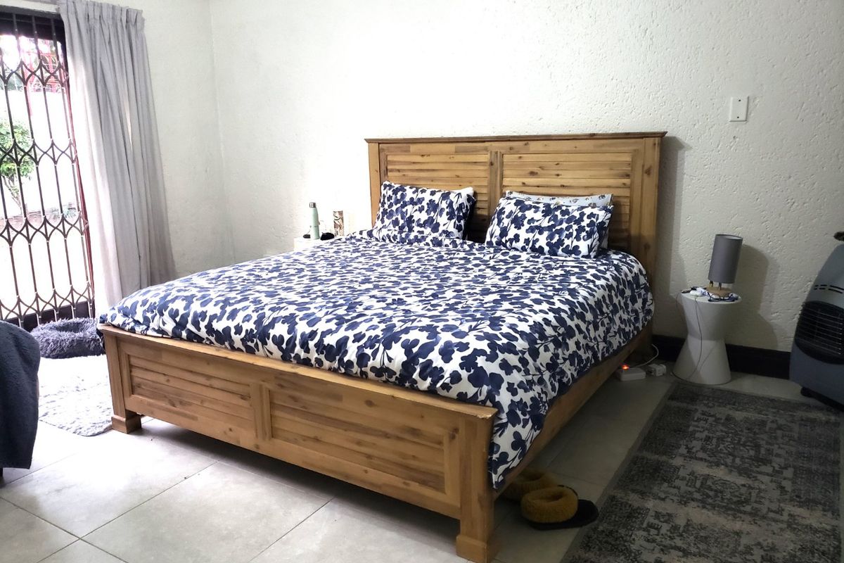 A bedroom featuring tiled flooring and a sliding glass door with an integrated security gate, providing access to the exterior.