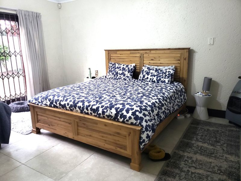 A bedroom featuring tiled flooring and a sliding glass door with an integrated security gate, providing access to the exterior.