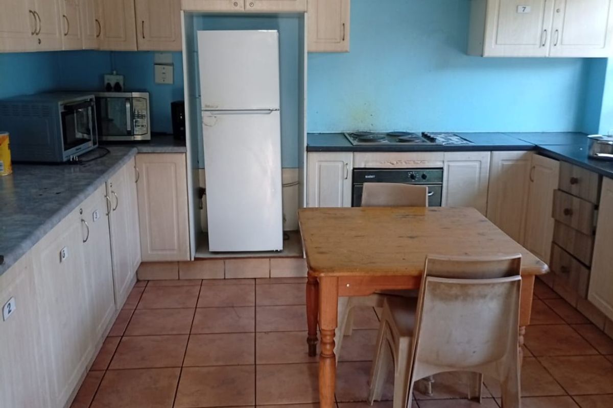 A dated kitchen featuring light wood-tone cabinetry, tiled flooring, and a built-in oven with electric hob, offering potential for a modern renovation.
