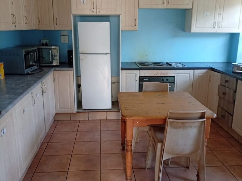 A dated kitchen featuring light wood-tone cabinetry, tiled flooring, and a built-in oven with electric hob, offering potential for a modern renovation.