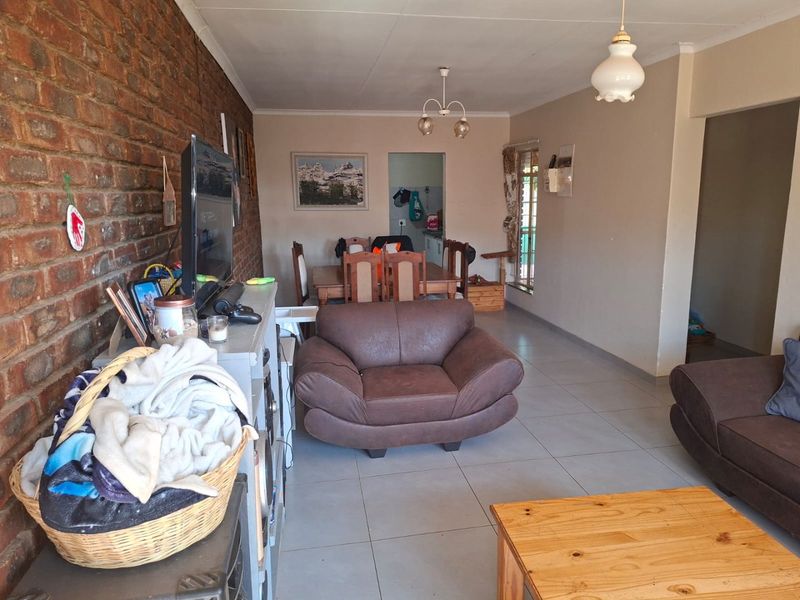Open-plan living and dining area featuring tiled flooring and an exposed brick feature wall, providing a functional and connected living space.
