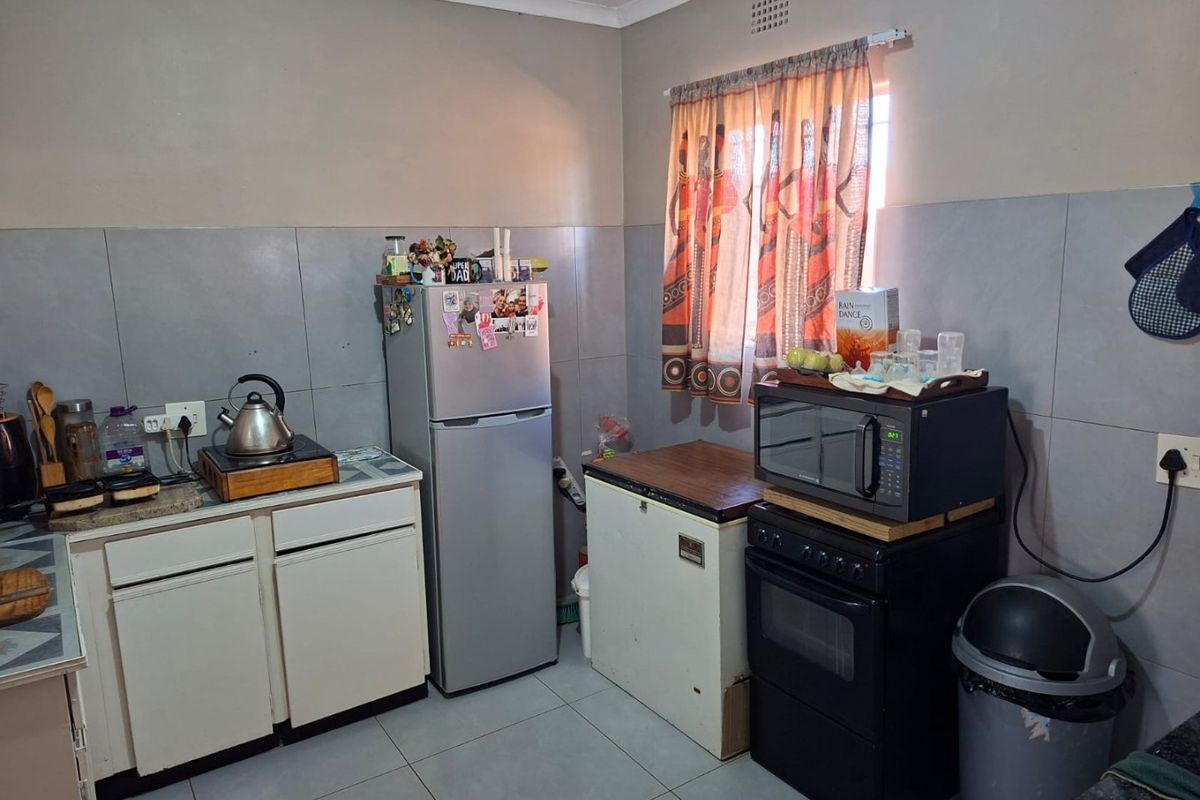 A functional kitchen featuring tiled splashbacks, floor tiles, and built-in cabinetry, offering a practical layout for daily meal preparation.
