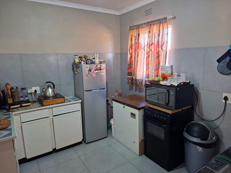 A functional kitchen featuring tiled splashbacks, floor tiles, and built-in cabinetry, offering a practical layout for daily meal preparation.