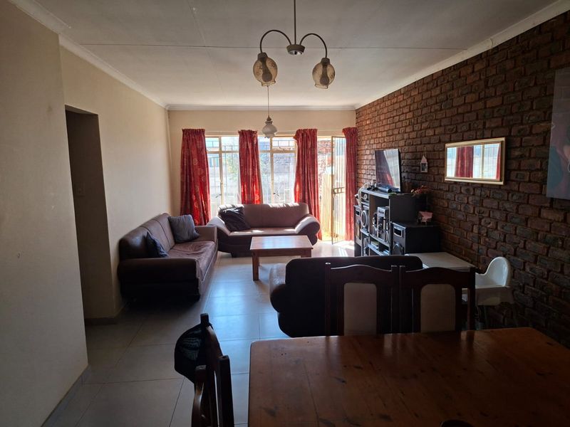 Open plan living and dining area featuring an exposed brick wall, tiled flooring, and direct access to the exterior through a sliding glass door.