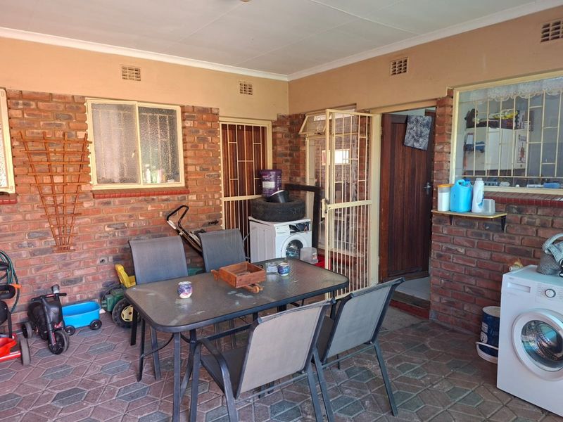 A covered outdoor patio area featuring exposed brick walls, paved flooring, and secure access points, suitable for casual outdoor dining or utility use.
