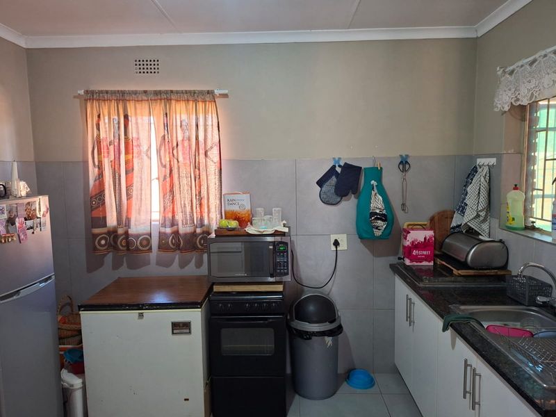 Functional kitchen featuring granite countertops, tiled splashbacks, and built-in cabinetry, providing a practical workspace with essential fixed appliances.