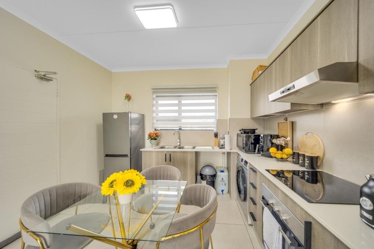 Modern kitchen featuring sleek cabinetry, integrated appliances, electric hob, extractor fan, and tiled flooring with a functional layout.