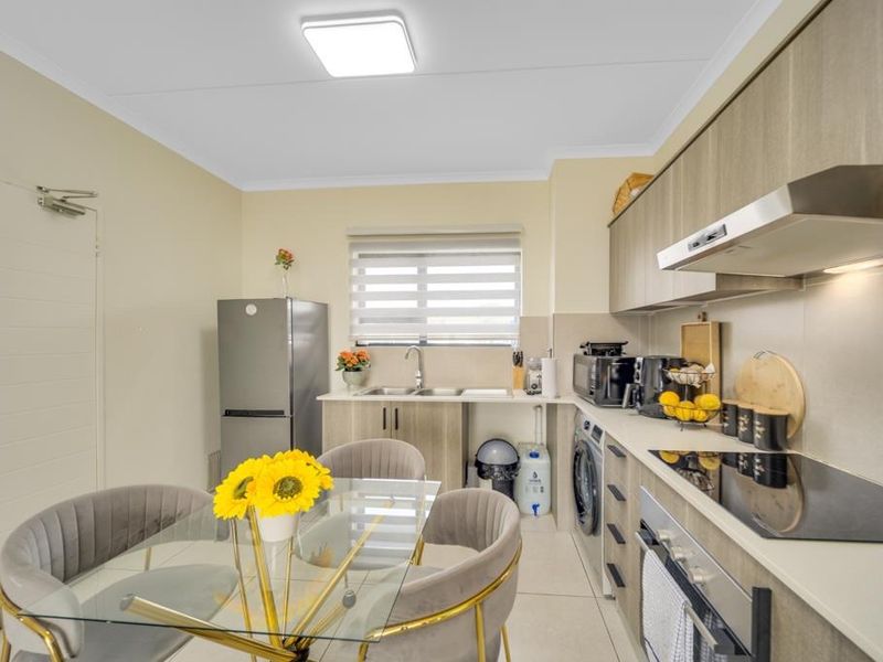 Modern kitchen featuring sleek cabinetry, integrated appliances, electric hob, extractor fan, and tiled flooring with a functional layout.
