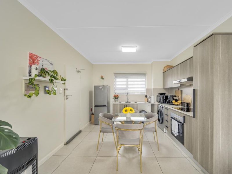 Modern open-plan kitchen and dining area featuring contemporary cabinetry, integrated appliances, tiled flooring, and neutral finishes throughout.