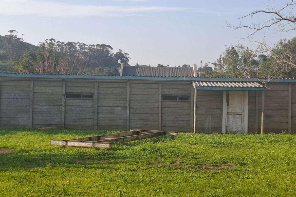 A view of the rear exterior of a precast concrete structure with a corrugated metal roof and a single timber door.