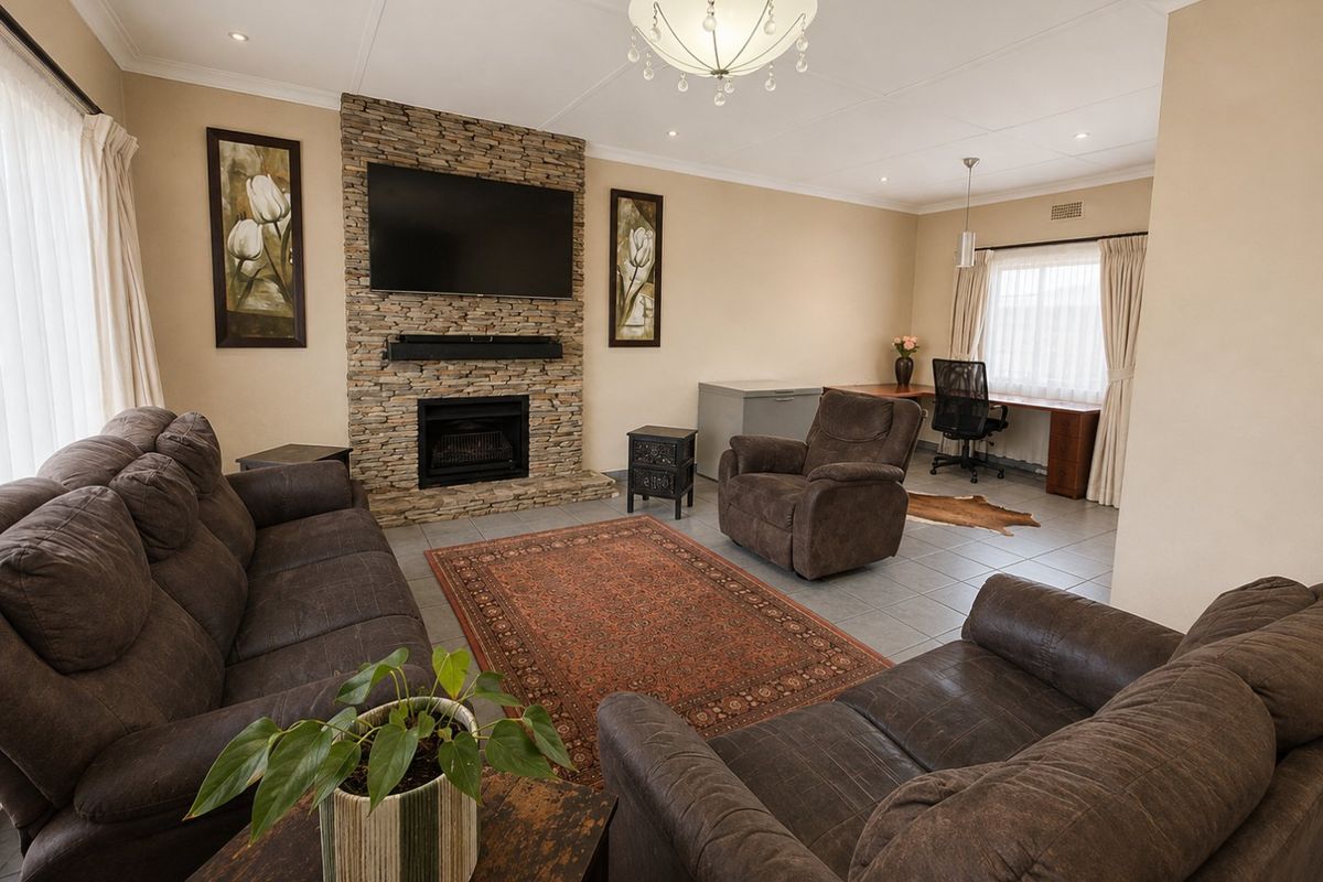 Spacious living room featuring a stone-clad fireplace, tiled flooring, and a dedicated built-in desk area, offering a comfortable and functional living space.
