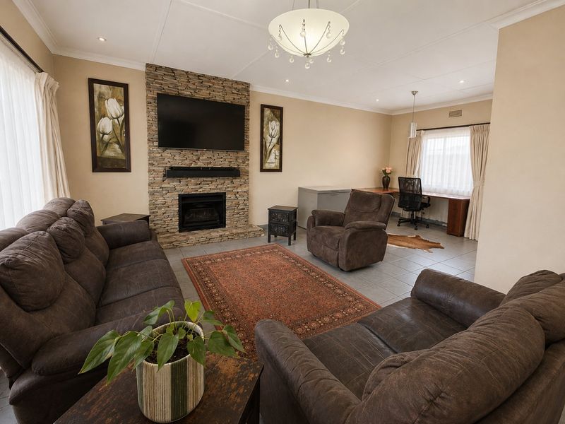 Spacious living room featuring a stone-clad fireplace, tiled flooring, and a dedicated built-in desk area, offering a comfortable and functional living space.