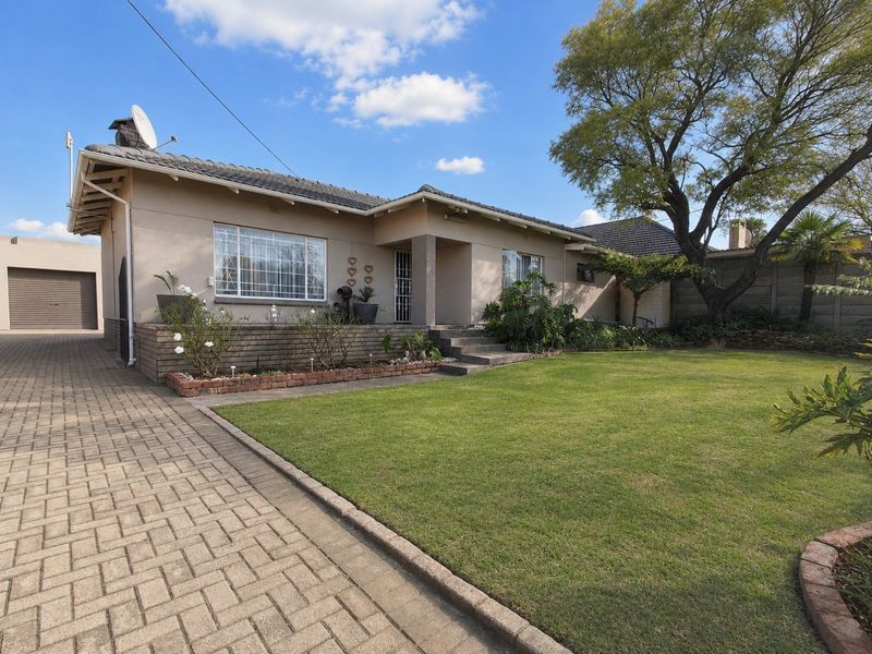 Front view of a single-story house featuring a tiled roof, brick driveway, and a well-maintained front garden with a concrete porch entrance.