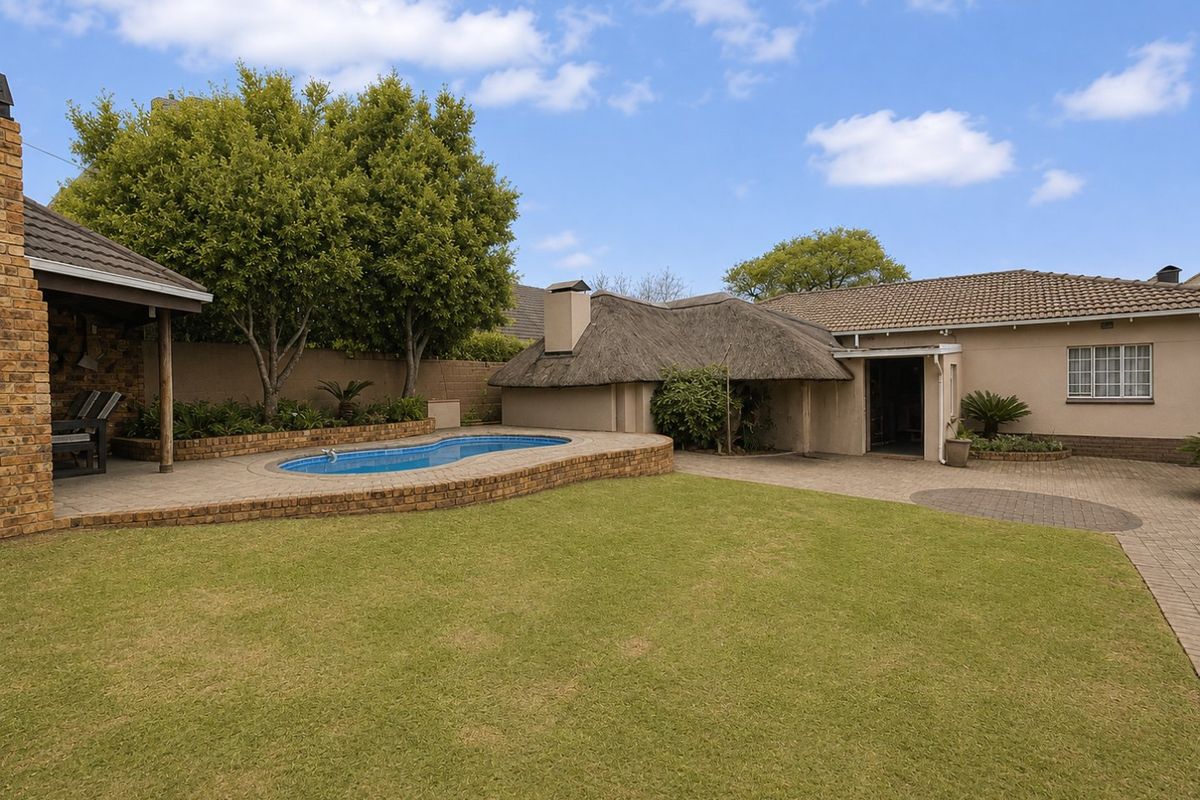 Rear garden featuring a swimming pool, paved patio area, and a structure with a traditional thatched roof.