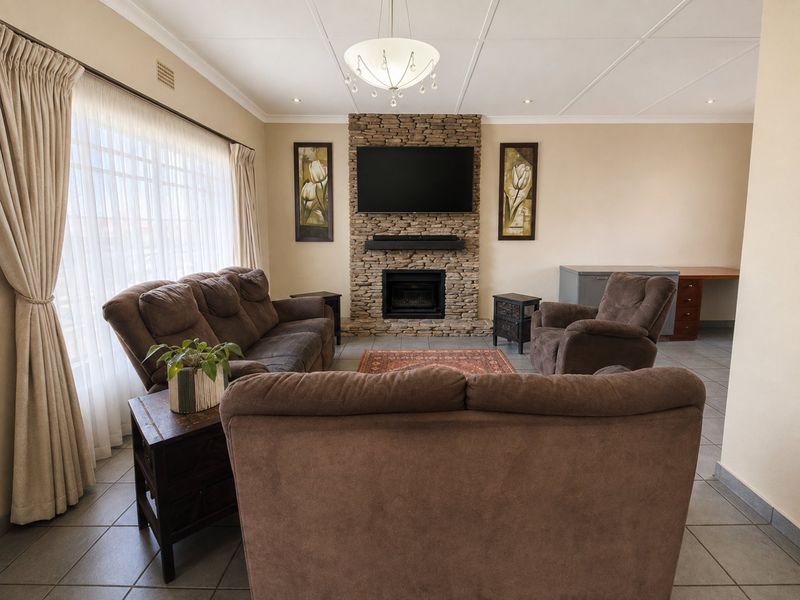 A comfortable living room featuring a prominent stone fireplace, tiled flooring, and a built-in desk area, offering a warm and functional space.